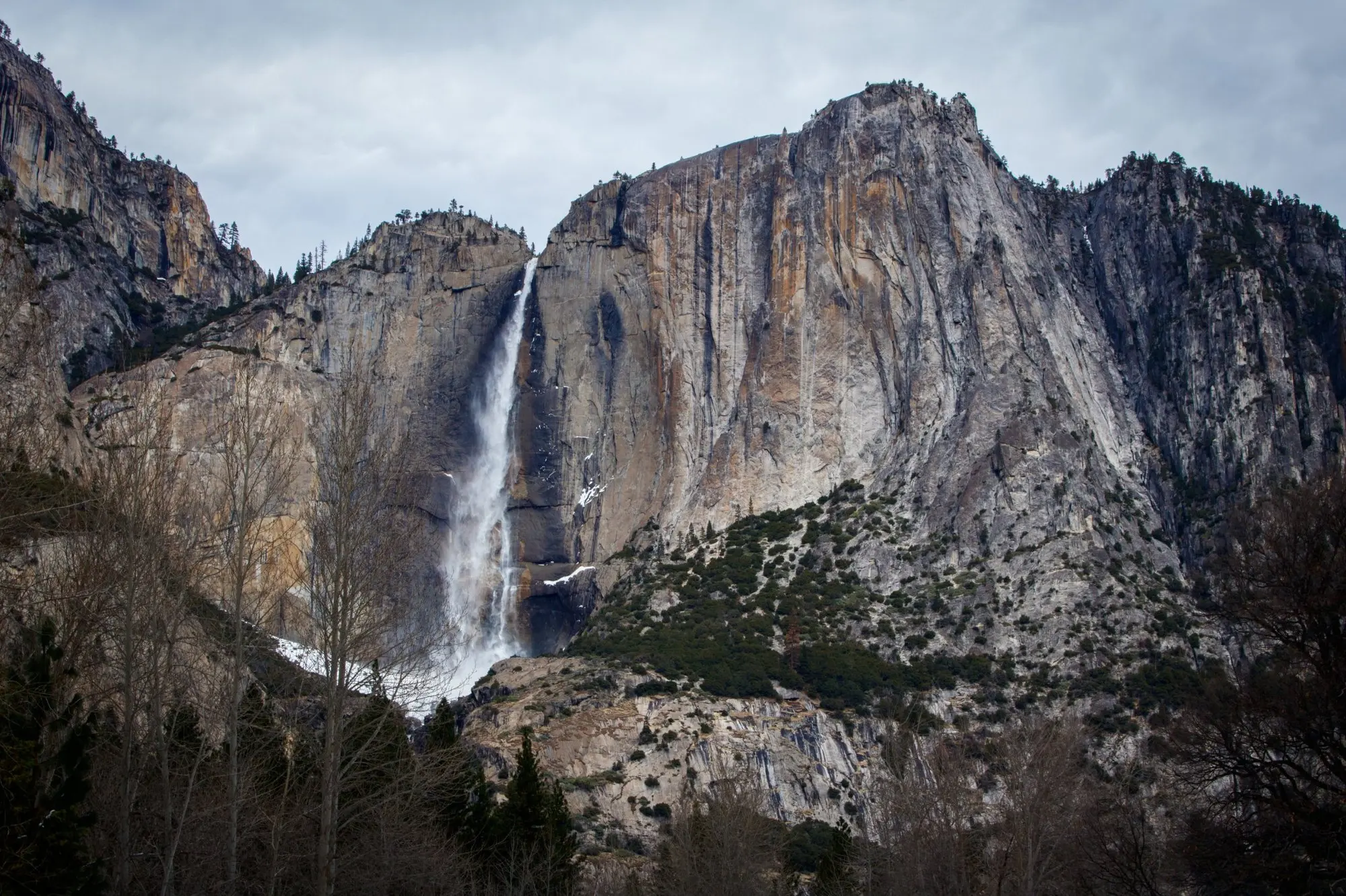 Yosemite Falls an einer grauen Felswand, davor kahle Bäume